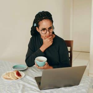 a woman sitting at a table with a laptop and a cup of tea
